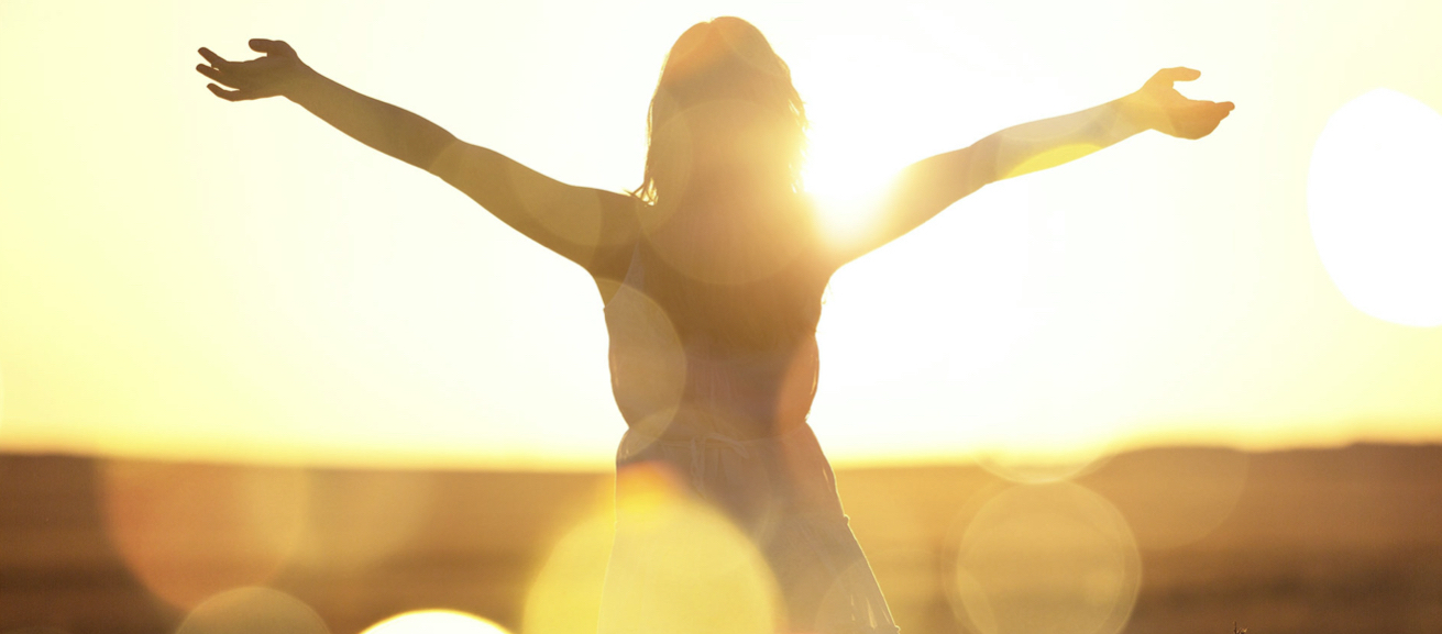 Person mit ausgestreckten Armen in der Sonne – Symbol für Befreiung und freies Atmen durch Hypnosetherapie